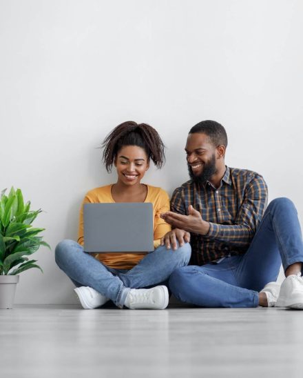 smiling-black-male-and-female-with-potted-plant-typing-on-computer-planning-interior-sit-on-floor.jpg